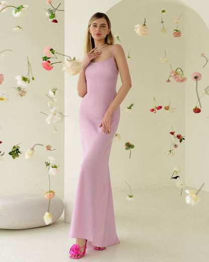 Woman in a pink dress standing in a room with floral decorations.