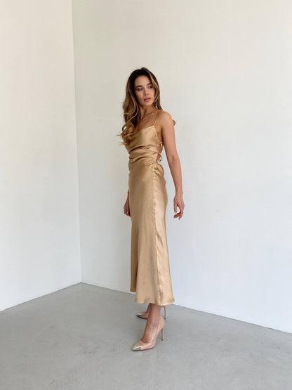 Woman wearing a gold satin dress against a white background