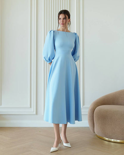 Woman wearing a light blue dress with puffed sleeves in an elegant room.