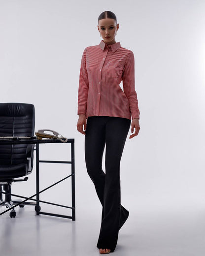 Woman wearing a red striped shirt and black pants standing in an office setting.