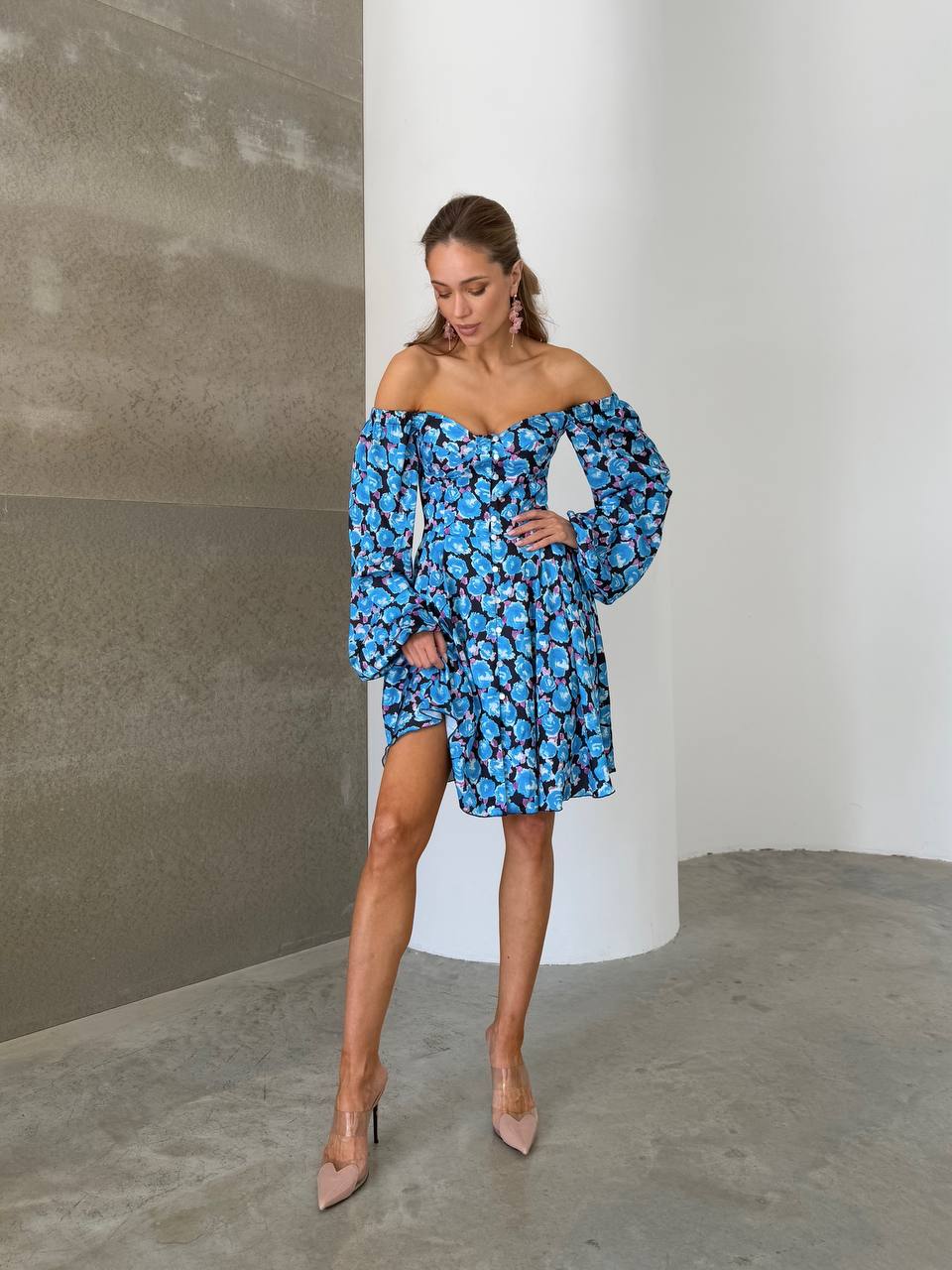 Woman wearing a blue floral off-shoulder dress against a neutral background