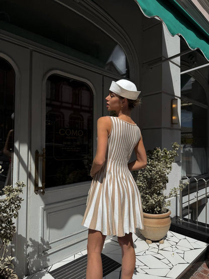 Woman in a striped dress standing outside a building with a green awning.