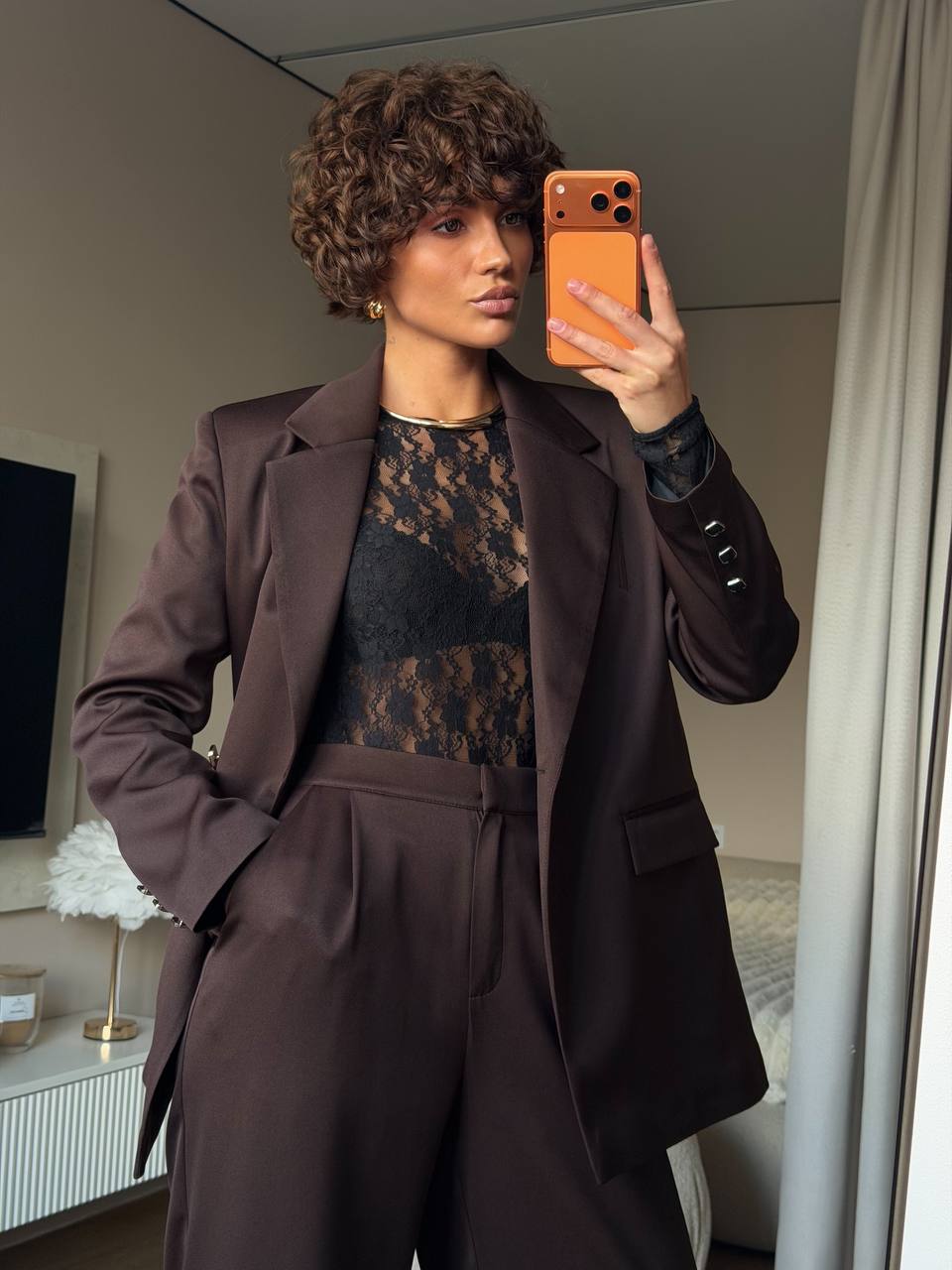 Person wearing a brown suit taking a mirror selfie.