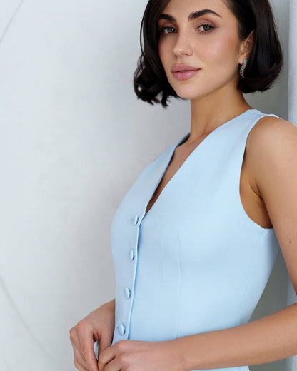 Woman wearing a light blue sleeveless dress against a white background