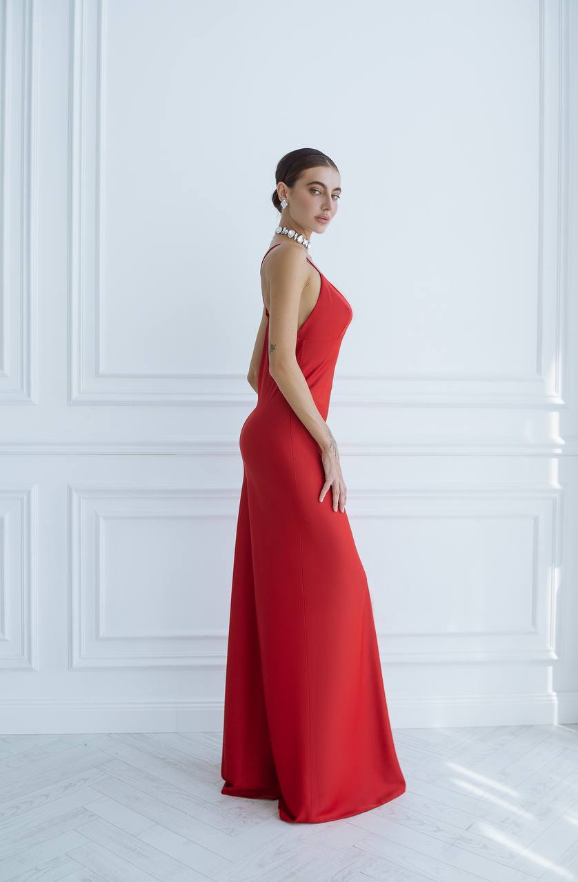 Woman wearing a red evening gown against a white wall
