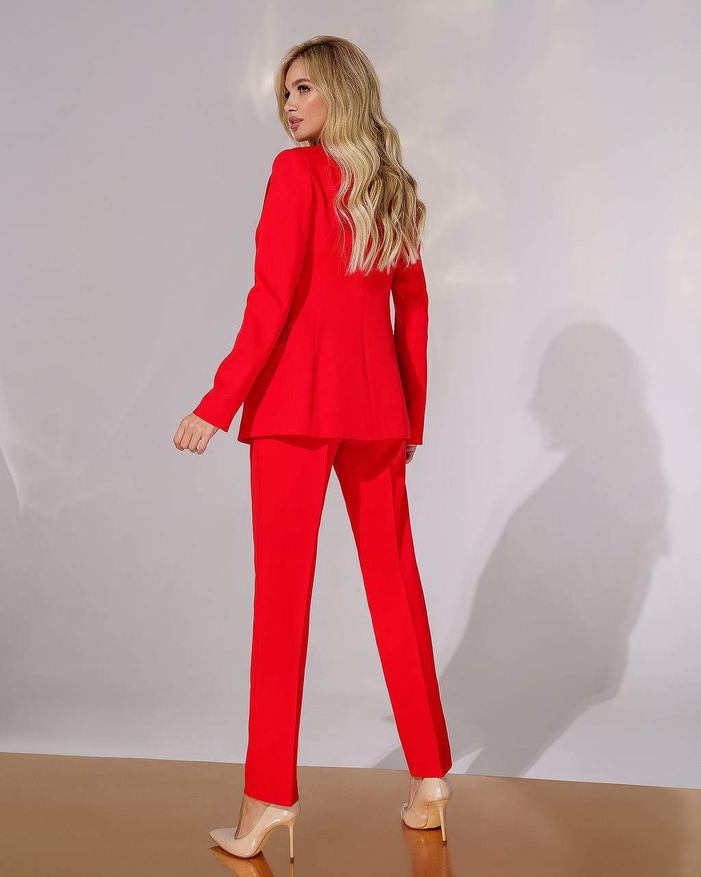 Woman wearing a red suit standing against a white background