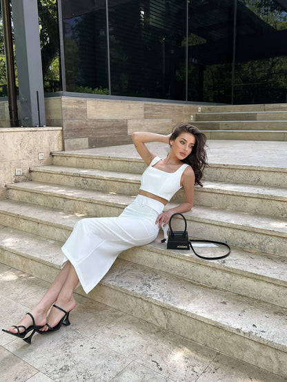 Woman in a white outfit sitting on stone steps outdoors