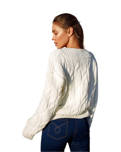 Woman wearing a white cable knit sweater and blue jeans on a white background
