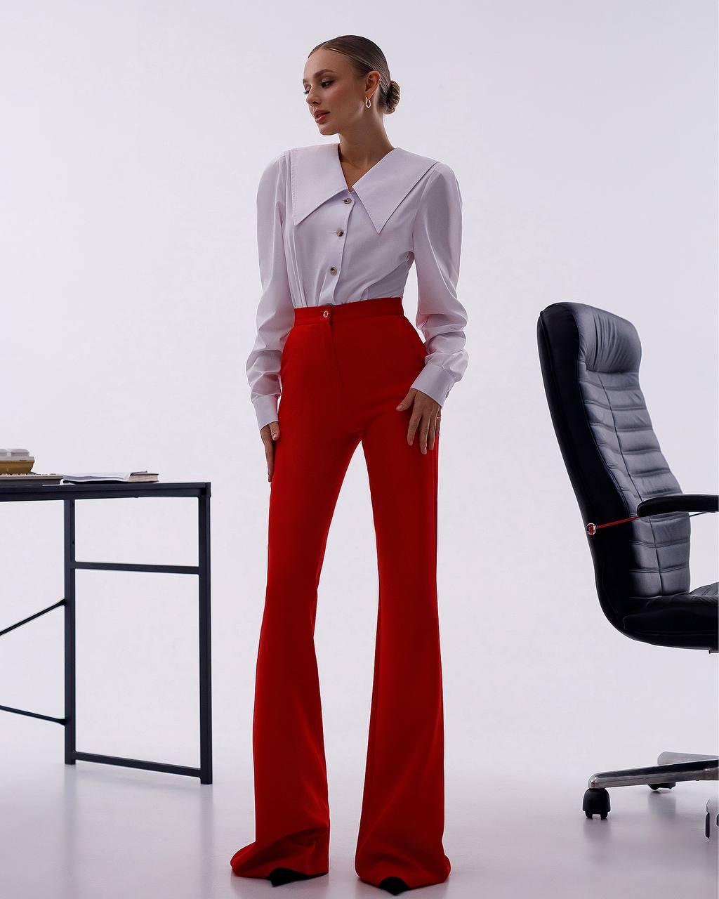 Person wearing a white blouse and red pants in an office setting