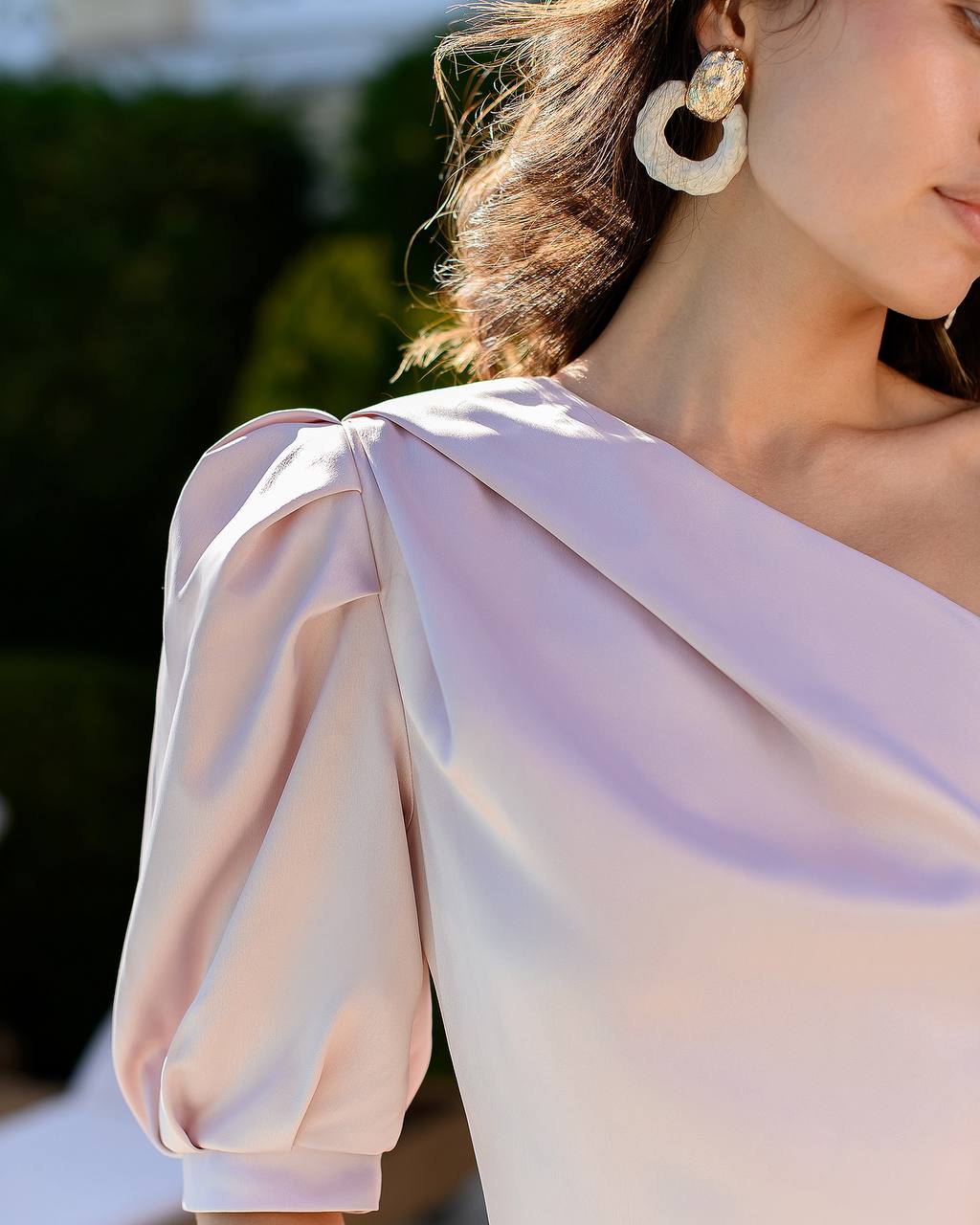 Close-up of a person wearing a light pink off-shoulder top with a blurred background