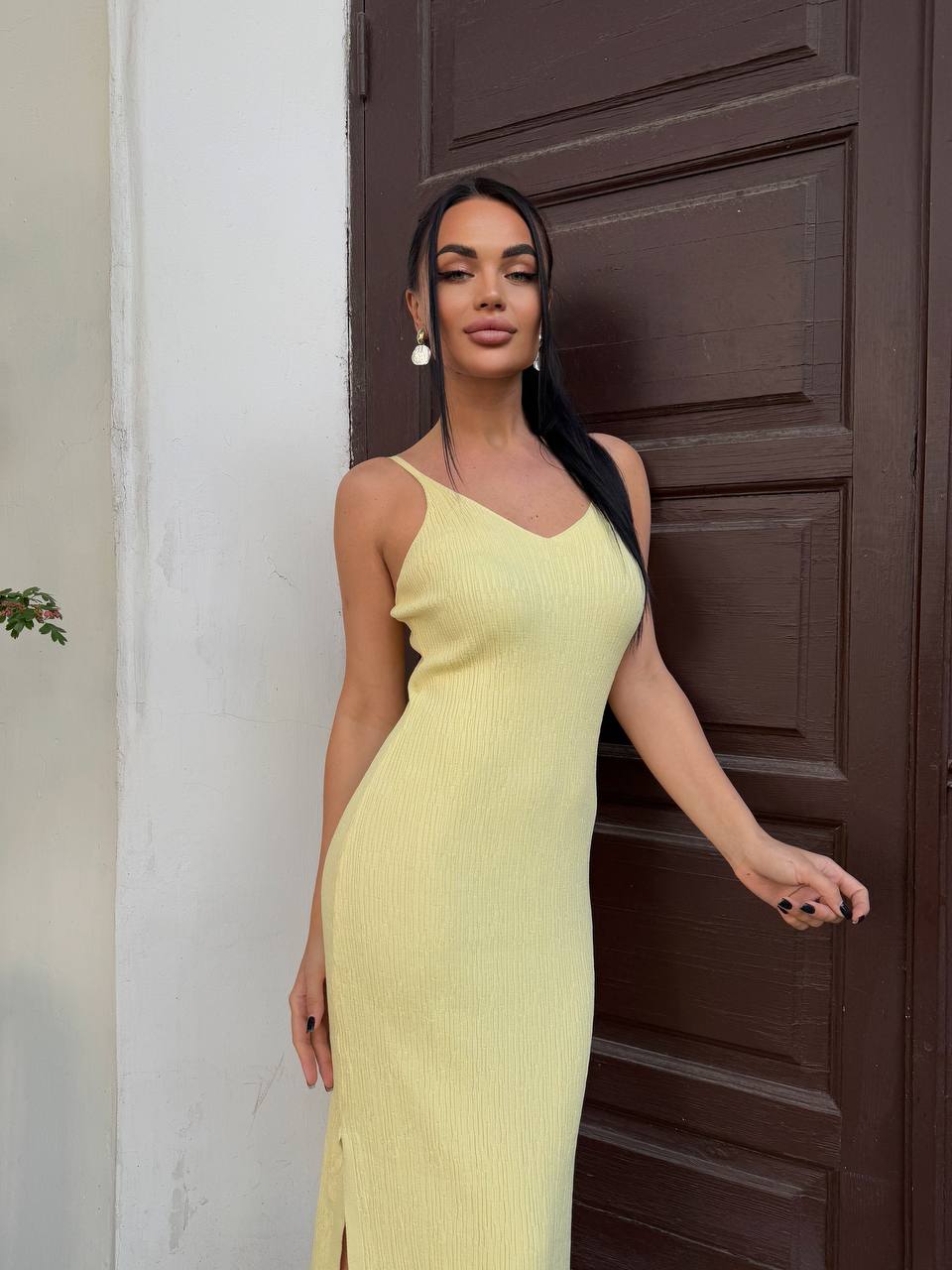 Woman in a yellow dress standing against a brown door.