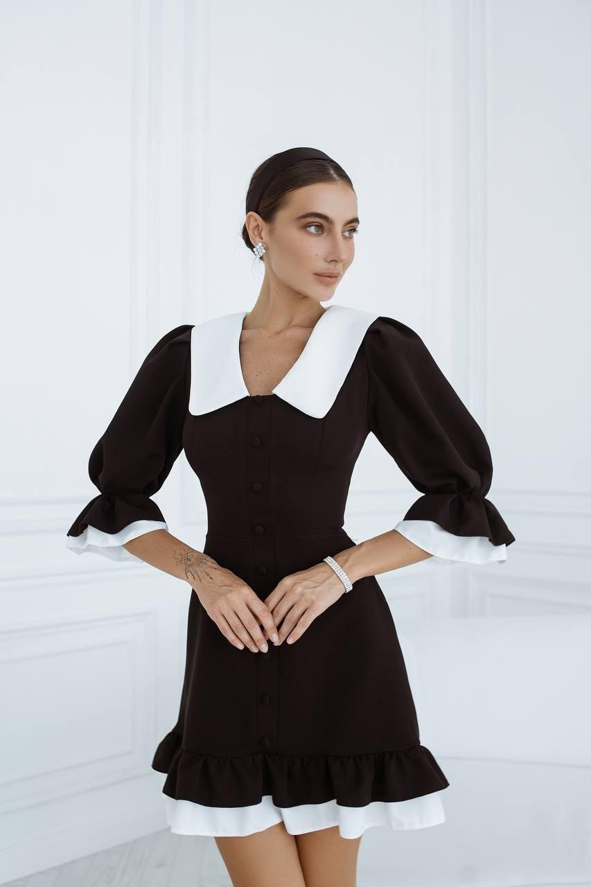 Woman wearing a black dress with white accents against a white background