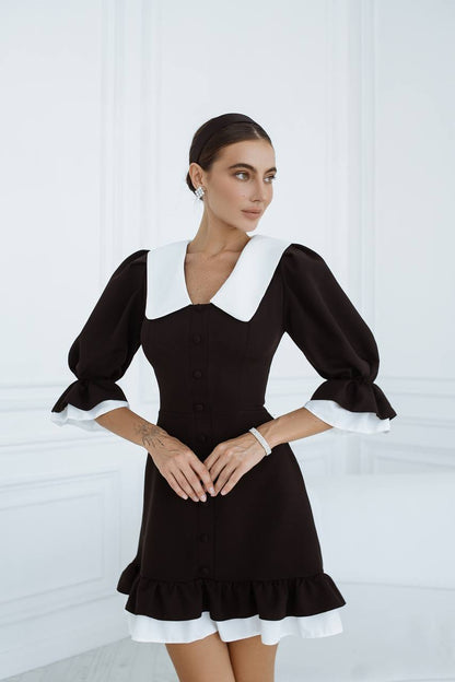 Woman wearing a black dress with white accents against a white background