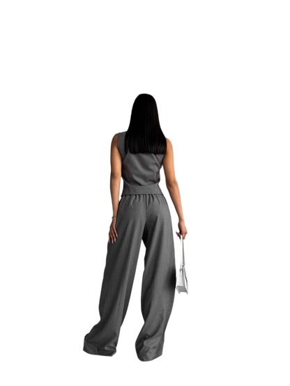Woman wearing a gray sleeveless top and wide-leg pants on a white background
