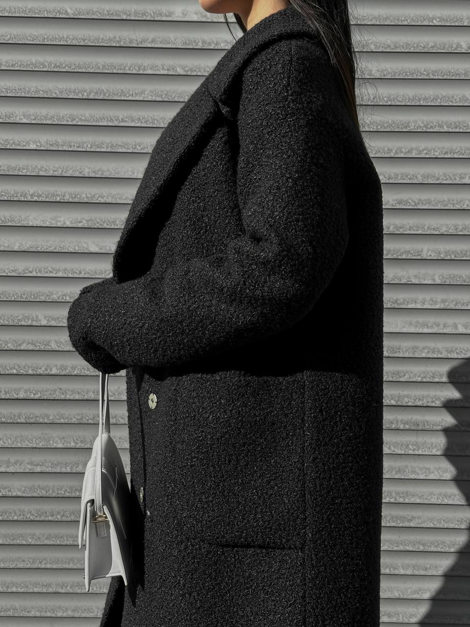 Person wearing a dark coat against a textured wall.