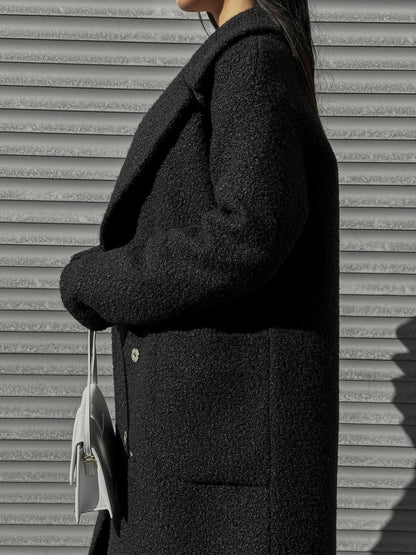 Person wearing a dark coat against a textured wall.