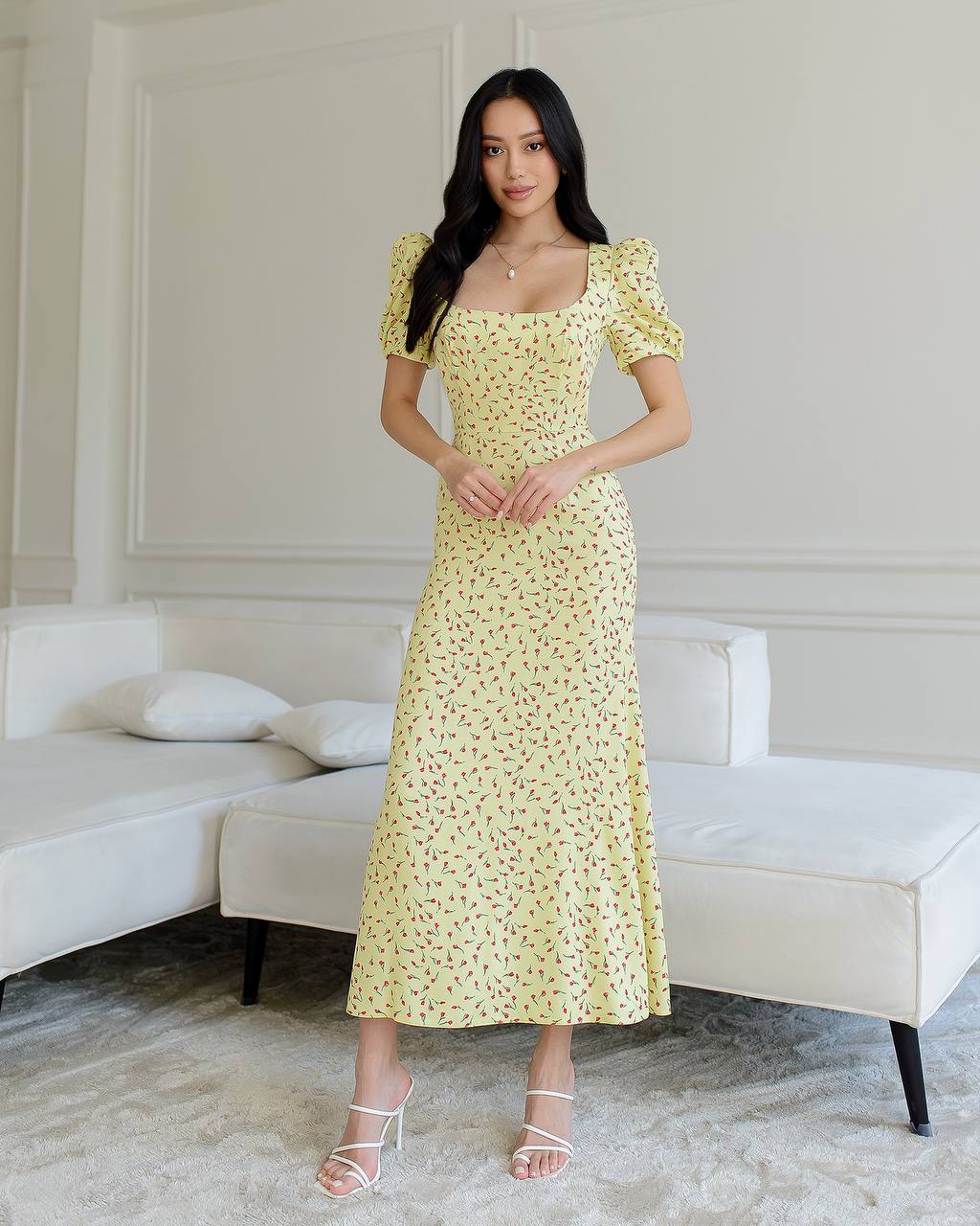Woman wearing a yellow floral dress in a modern living room.