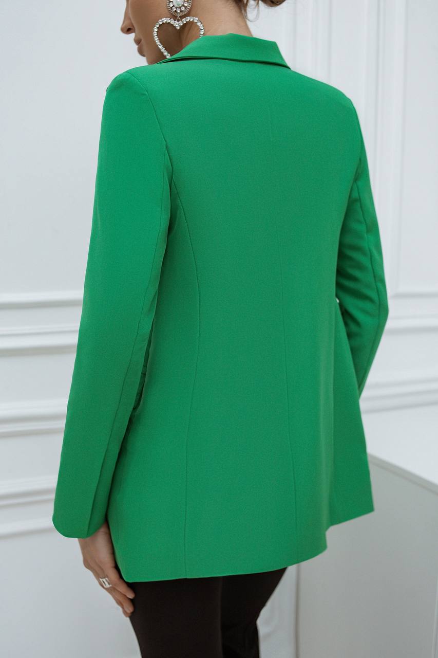 Green blazer worn by a person against a white wall
