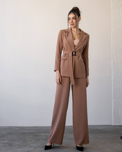 Woman wearing a brown suit standing against a plain background