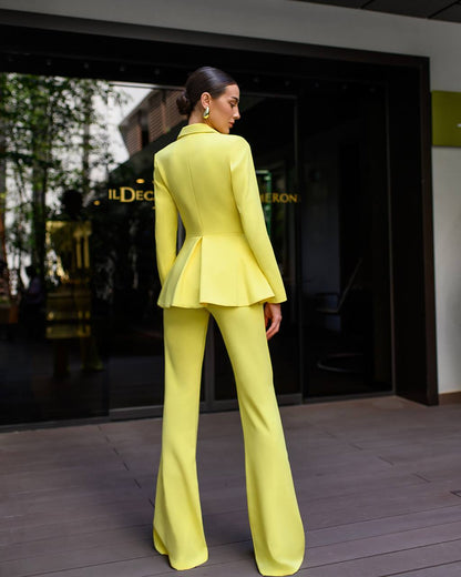 Woman in a bright yellow suit standing in front of a store entrance.
