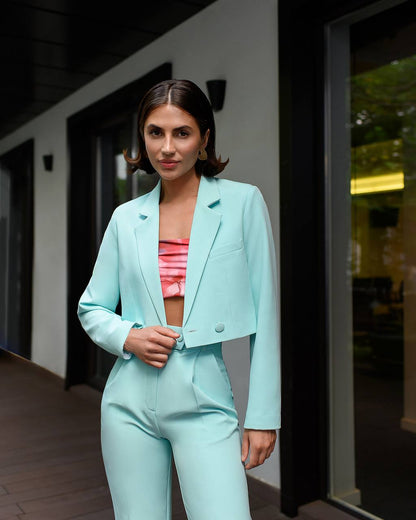 Woman wearing a light blue suit with a pink top outdoors.