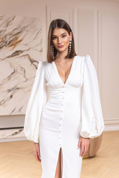 Woman wearing a white dress with long sleeves in an indoor setting