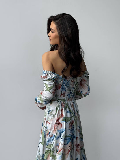 Woman wearing a floral off-shoulder dress against a plain background