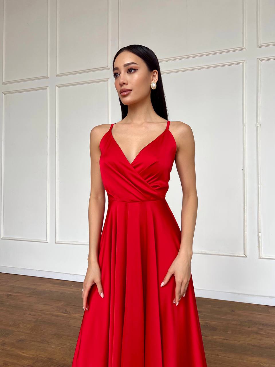 Woman wearing a red dress against a white paneled wall.