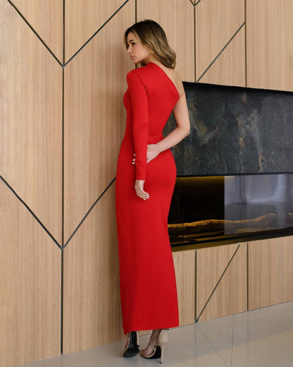Woman in a red dress standing against a modern interior wall.