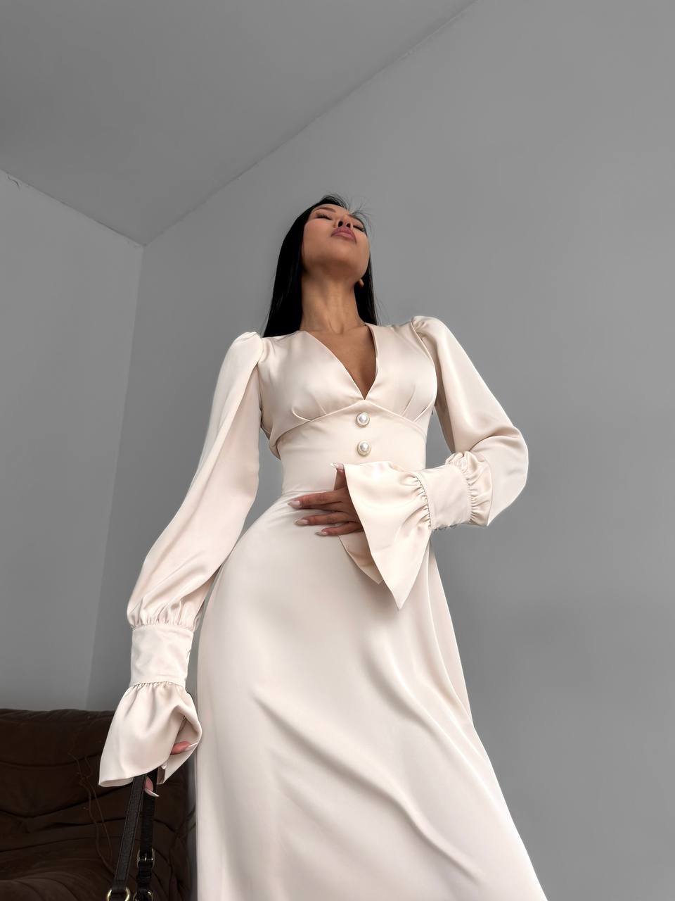 Woman wearing a white dress with long sleeves in a minimal indoor setting