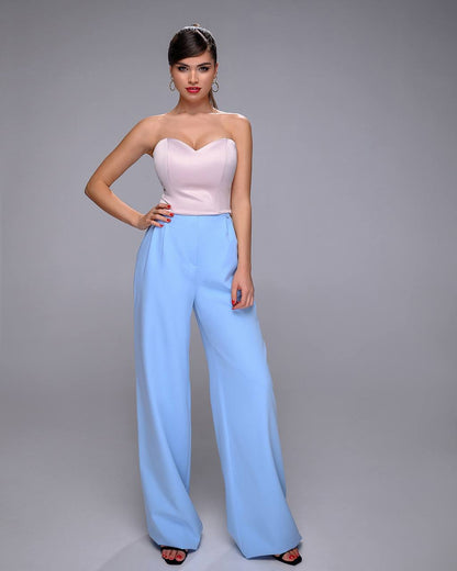 Woman wearing a strapless pink top and light blue pants on a gray background