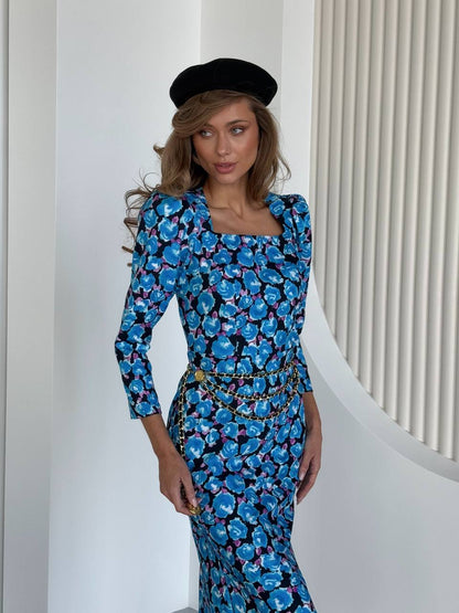 Woman wearing a blue floral dress with a black beret indoors.