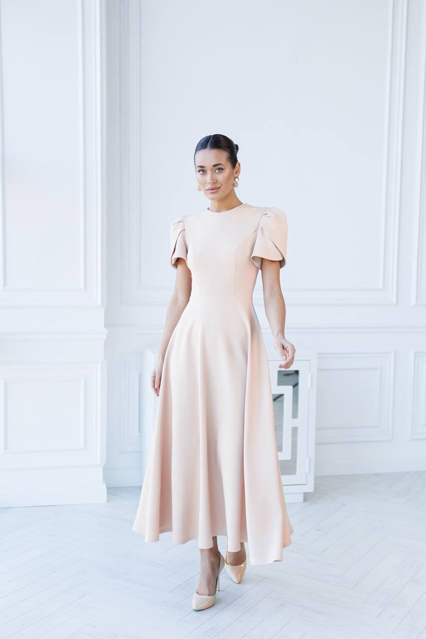 Woman wearing a light pink dress in a minimal white room