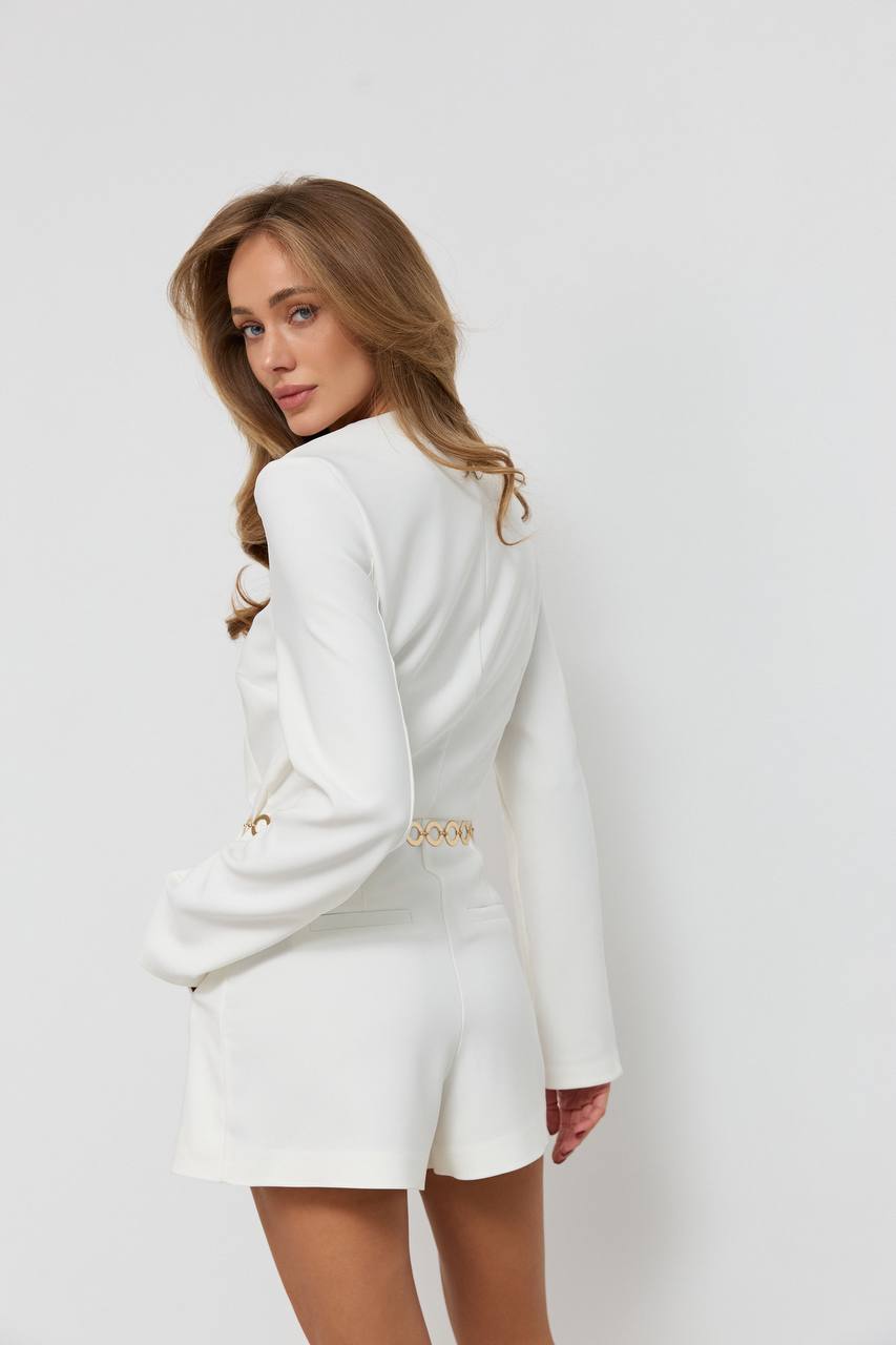 Woman wearing a white blazer and skirt set on a plain background