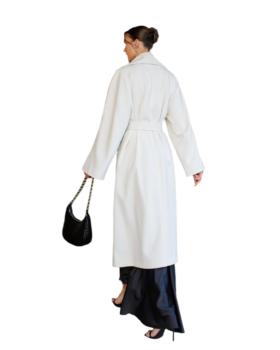 Woman wearing a white coat and black skirt with a black handbag on a white background