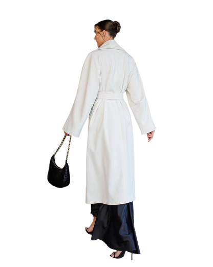 Woman wearing a white coat and black skirt with a black handbag on a white background