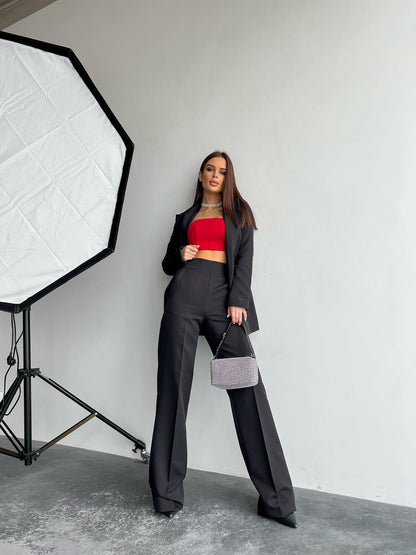 Woman in a black suit with a red top standing in front of a photography studio light setup.