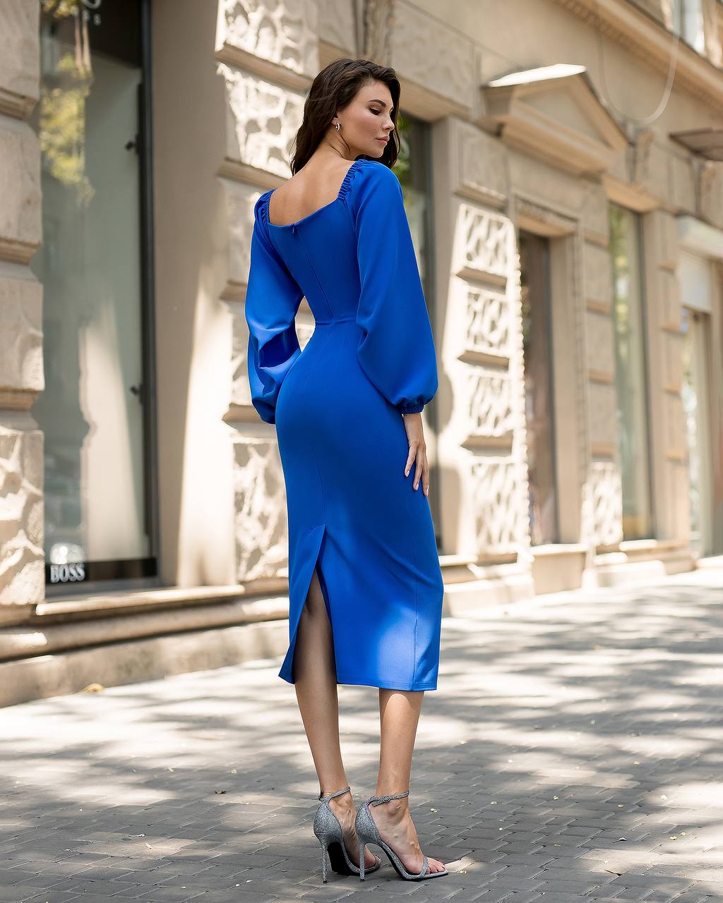 Woman in a blue dress standing on a street with a building in the background