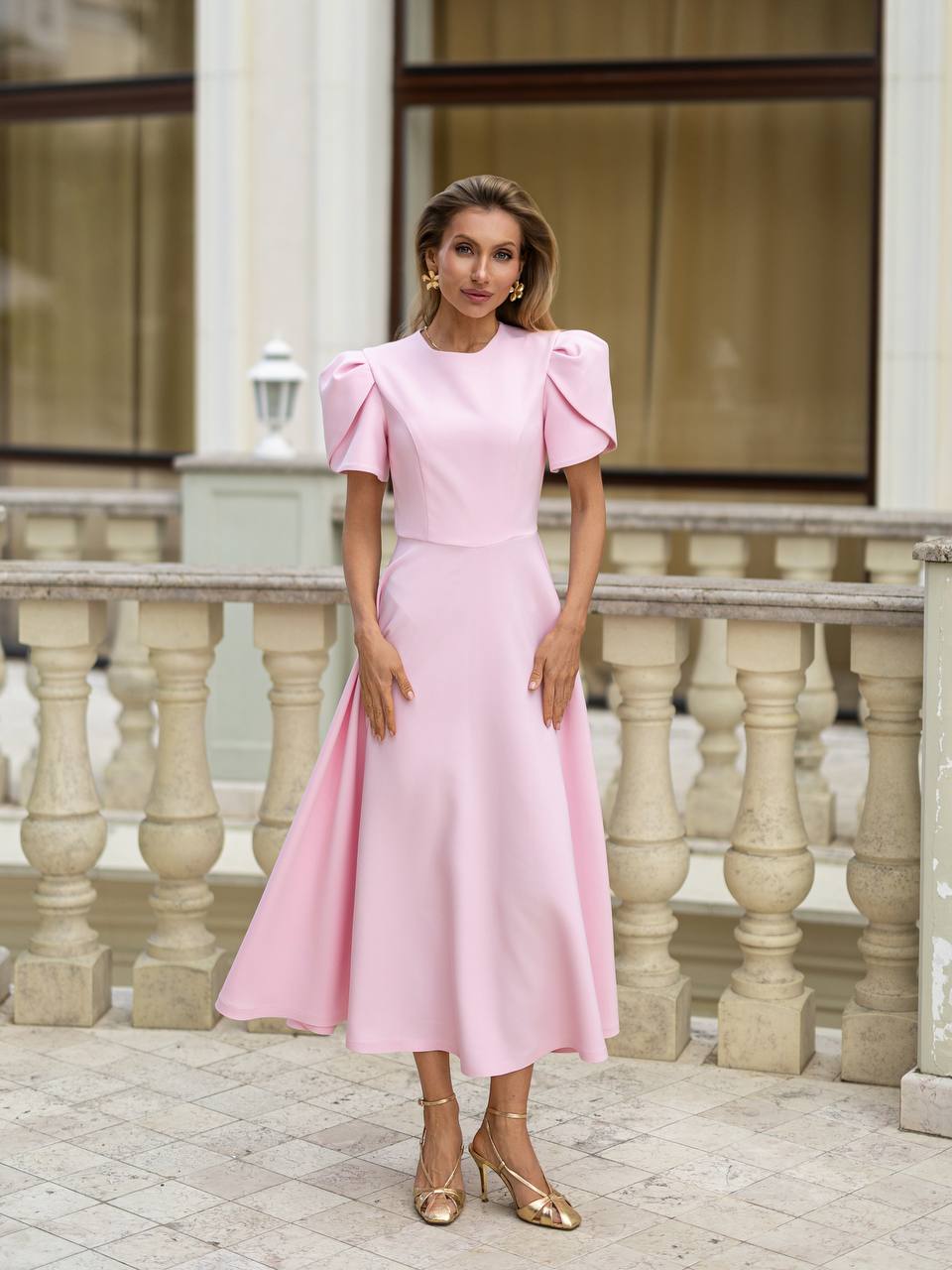 Woman in a pink dress standing in front of classical architecture