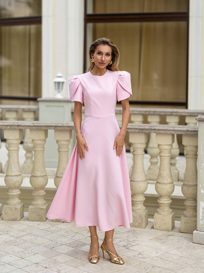 Woman in a pink dress standing in front of classical architecture