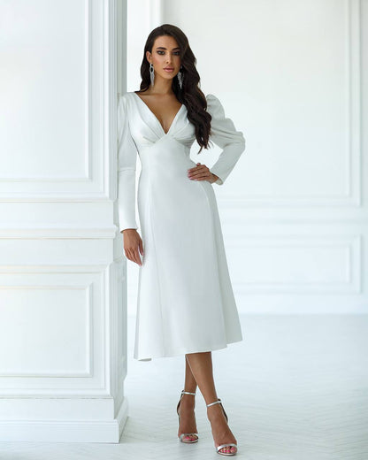 Woman wearing a white dress with long sleeves in a minimalistic setting
