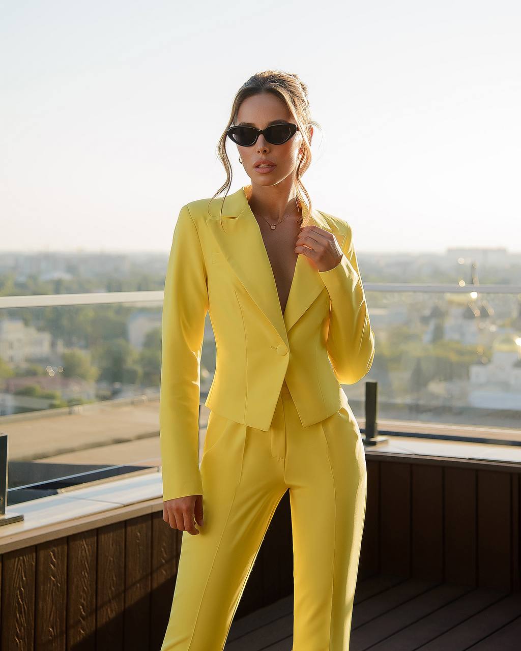 Person wearing a bright yellow suit standing on a rooftop with a cityscape background
