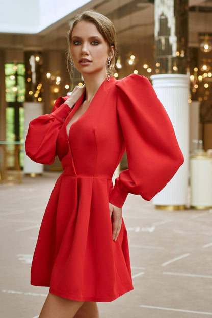 Woman wearing a red dress with puffed sleeves in an indoor setting.