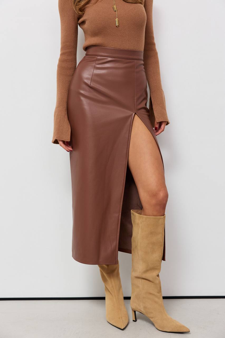 Person wearing a brown leather skirt and matching knee-high boots against a white background