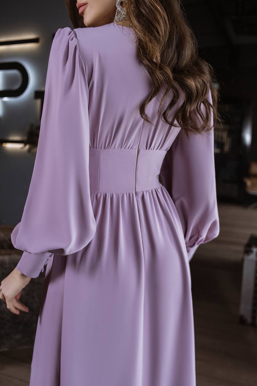 Woman wearing a lavender dress with long sleeves in an indoor setting