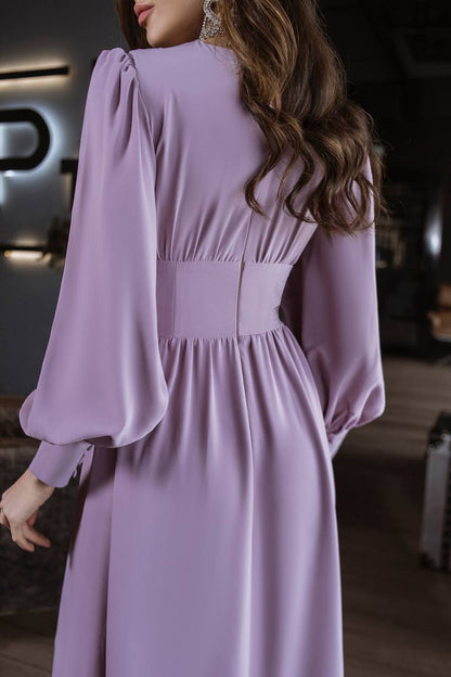 Woman wearing a lavender dress with long sleeves in an indoor setting
