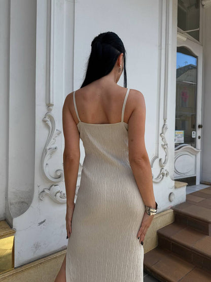 Woman in a beige dress standing in front of a decorative white door.