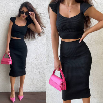 Woman wearing a black outfit with a pink handbag against a neutral background