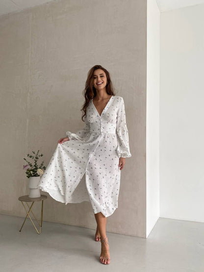 Woman wearing a white dress with a subtle pattern in a minimalistic setting.