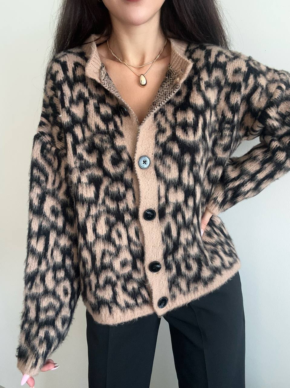 Person wearing a leopard print cardigan with a plain background